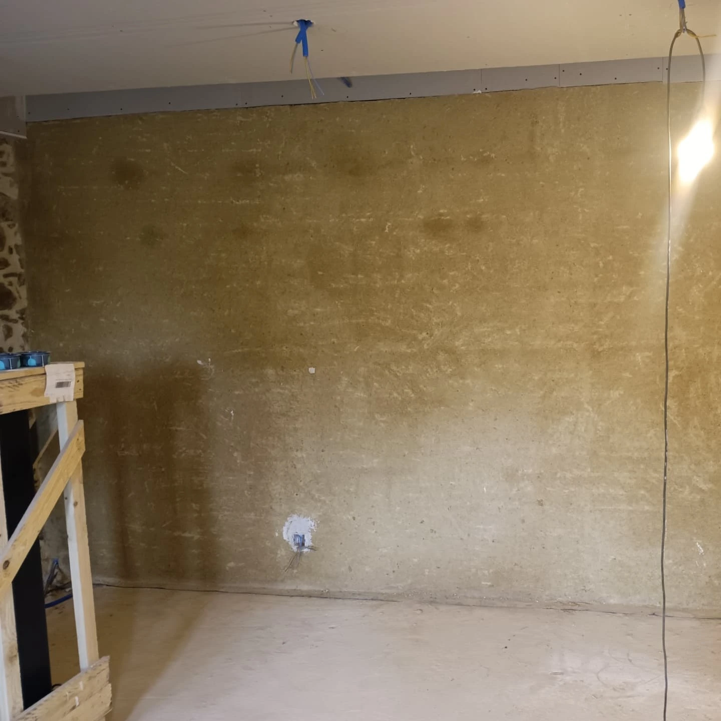 Mur en terre enduit à la chaux dans une pièce en rénovation