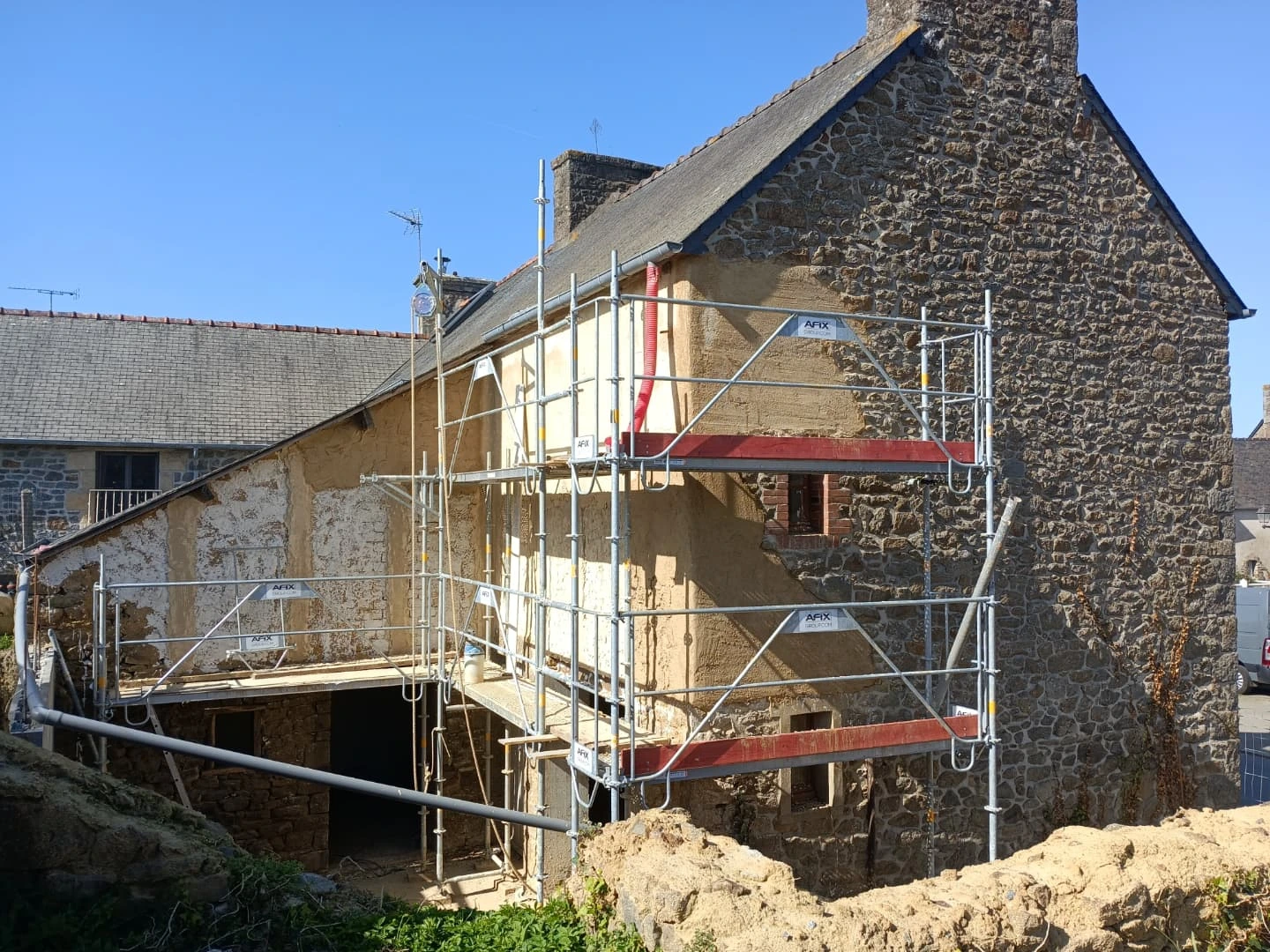 Longère en pierre sous échafaudage pendant la reprise d'enduit